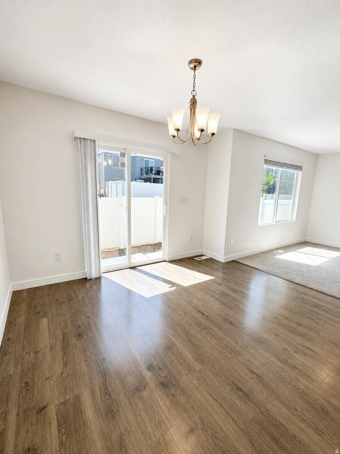 Dining are featuring wood-finish flooring, a contemporary chandelier, white walls, and a sliding glass door