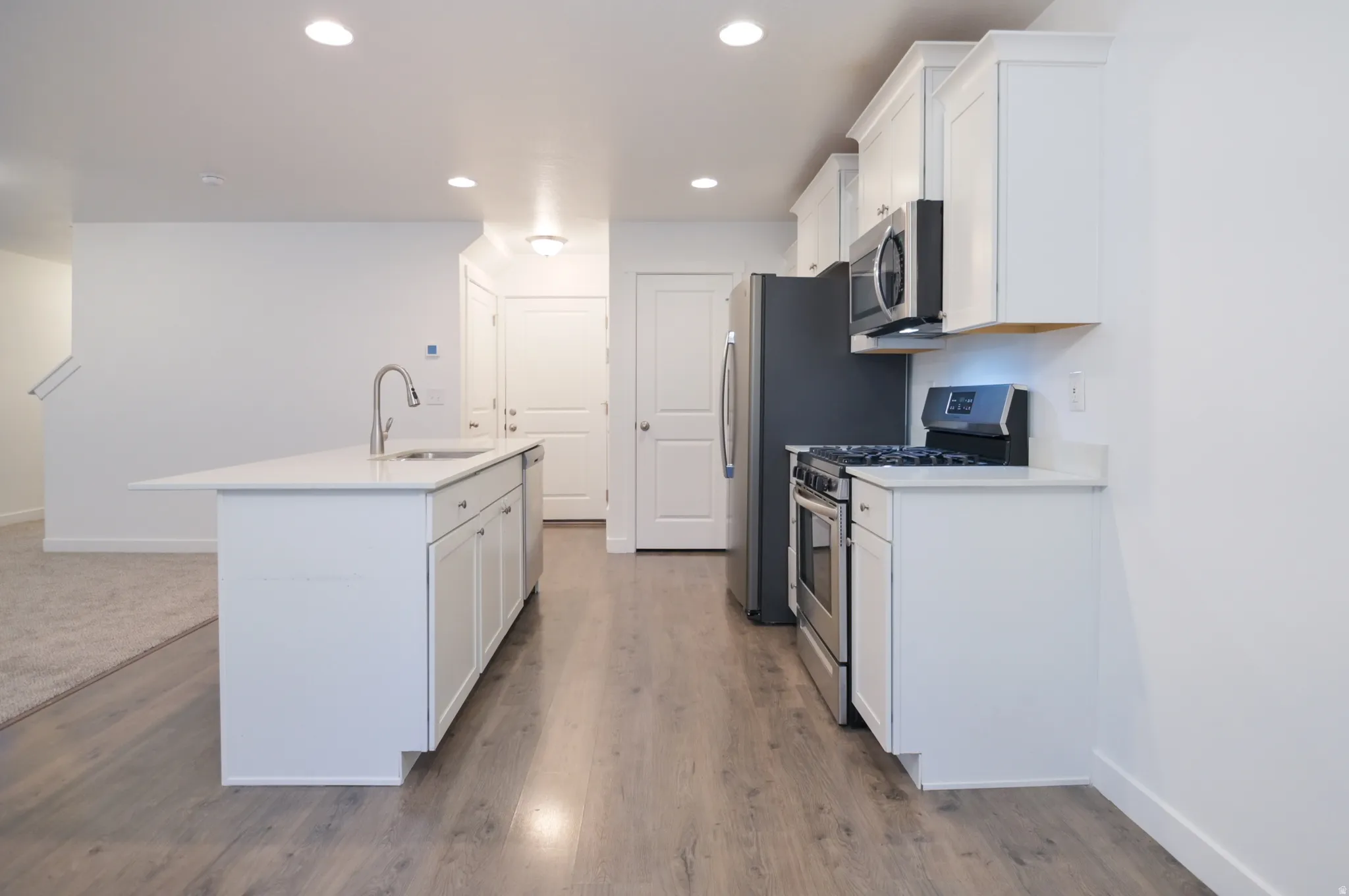 Contemporary kitchen featuring white cabinetry, light-toned wood-finish flooring, and recessed lighting