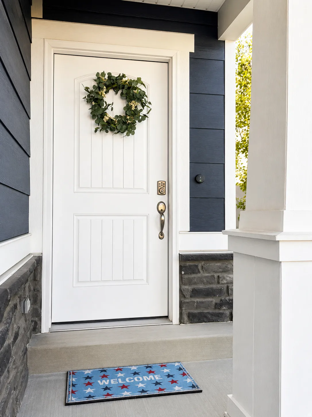 Entryway featuring a white paneled door, dark blue siding, stone facade, and a concrete porch