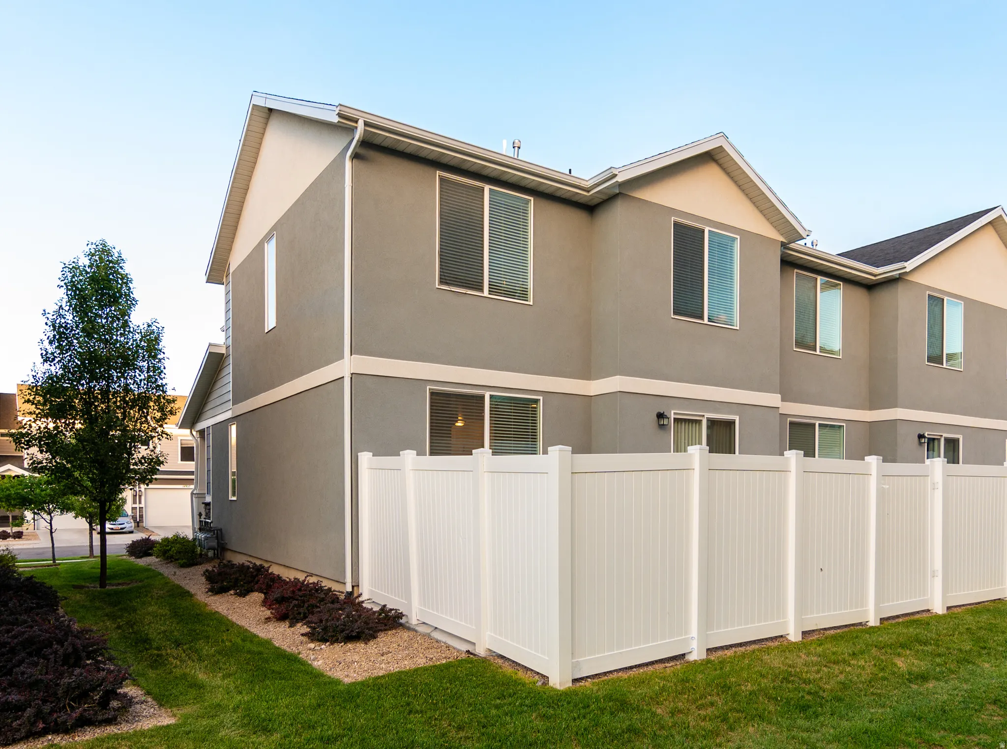 Two-story townhome with a grey stucco exterior and white trim