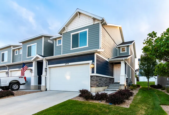 Contemporary residence featuring multi-toned siding, a stone facade accent, and a two-car garage