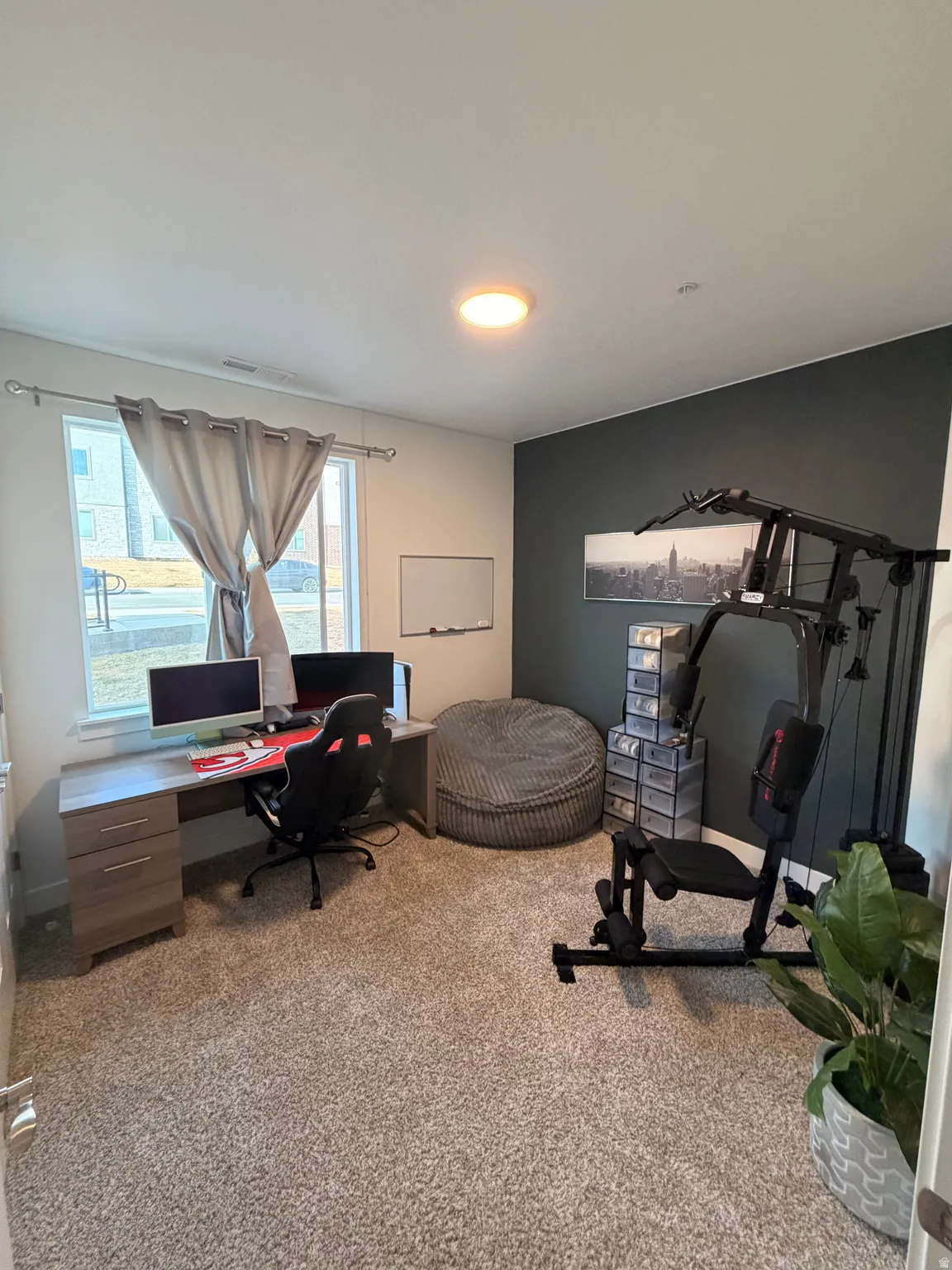 Carpeted room with a feature wall, window with curtains, and a flush mount ceiling light