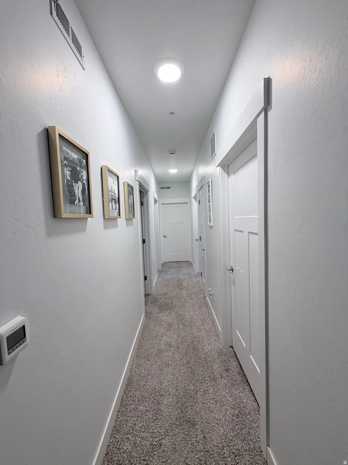 Hallway featuring light-toned carpeting, white walls, and recessed lighting