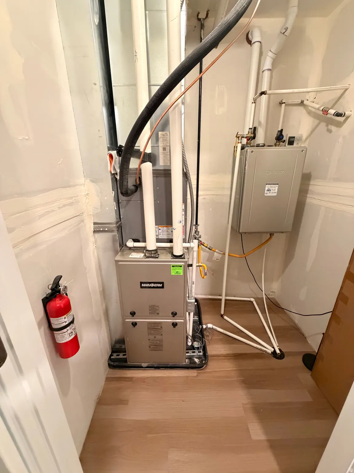 Dedicated utility area featuring a furnace system and a tankless water heater
