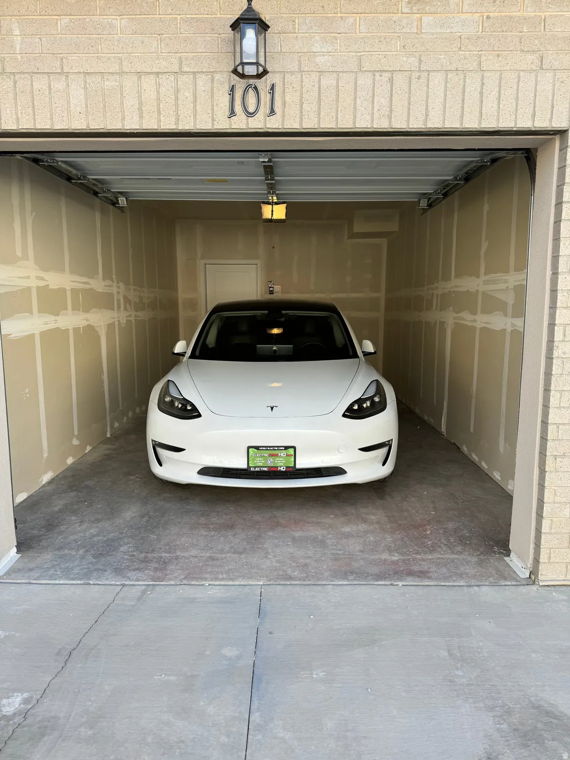 Single-car garage with concrete flooring, finished drywall, and overhead lighting
