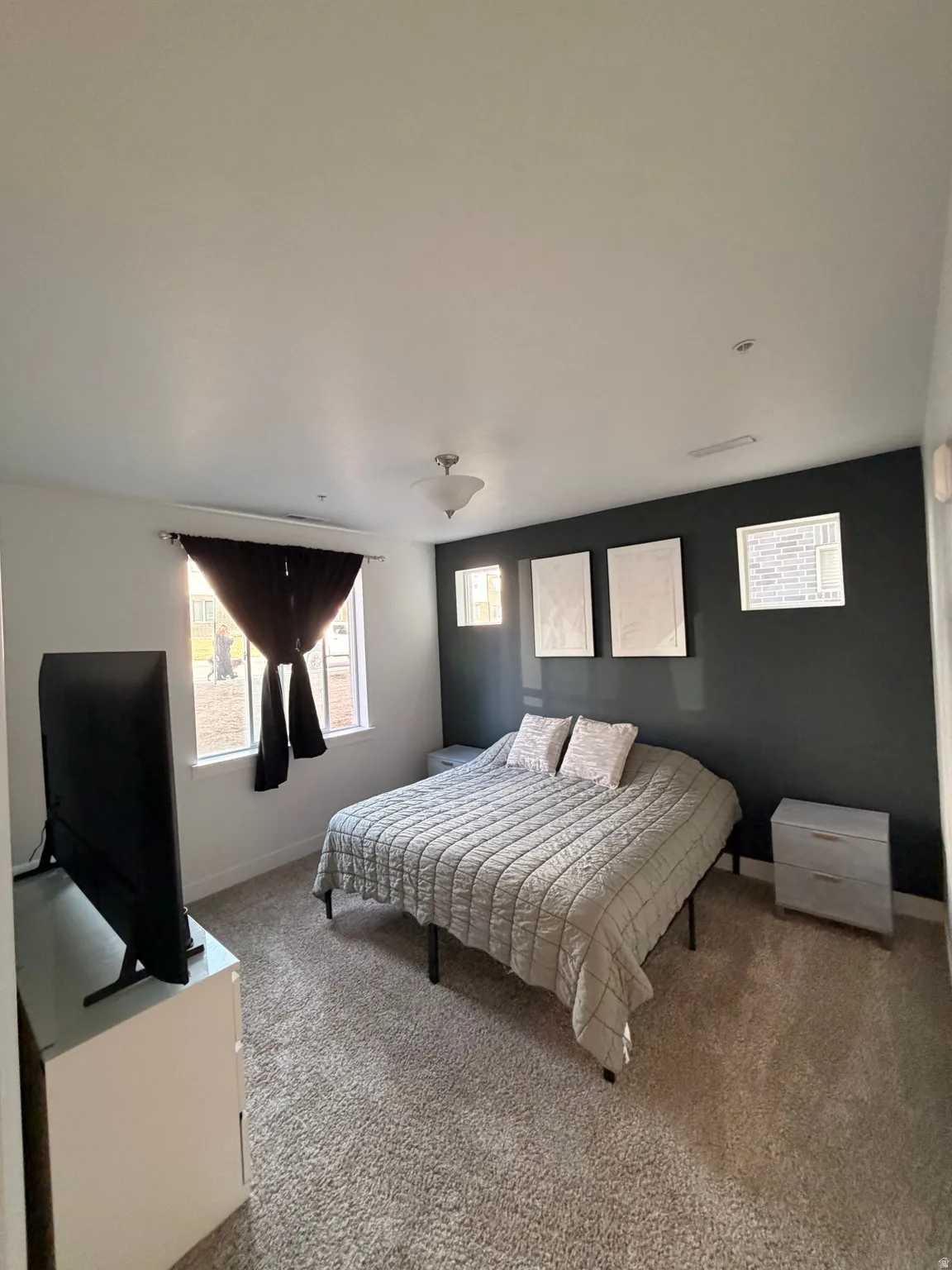Carpeted room featuring a single window with dark drapery