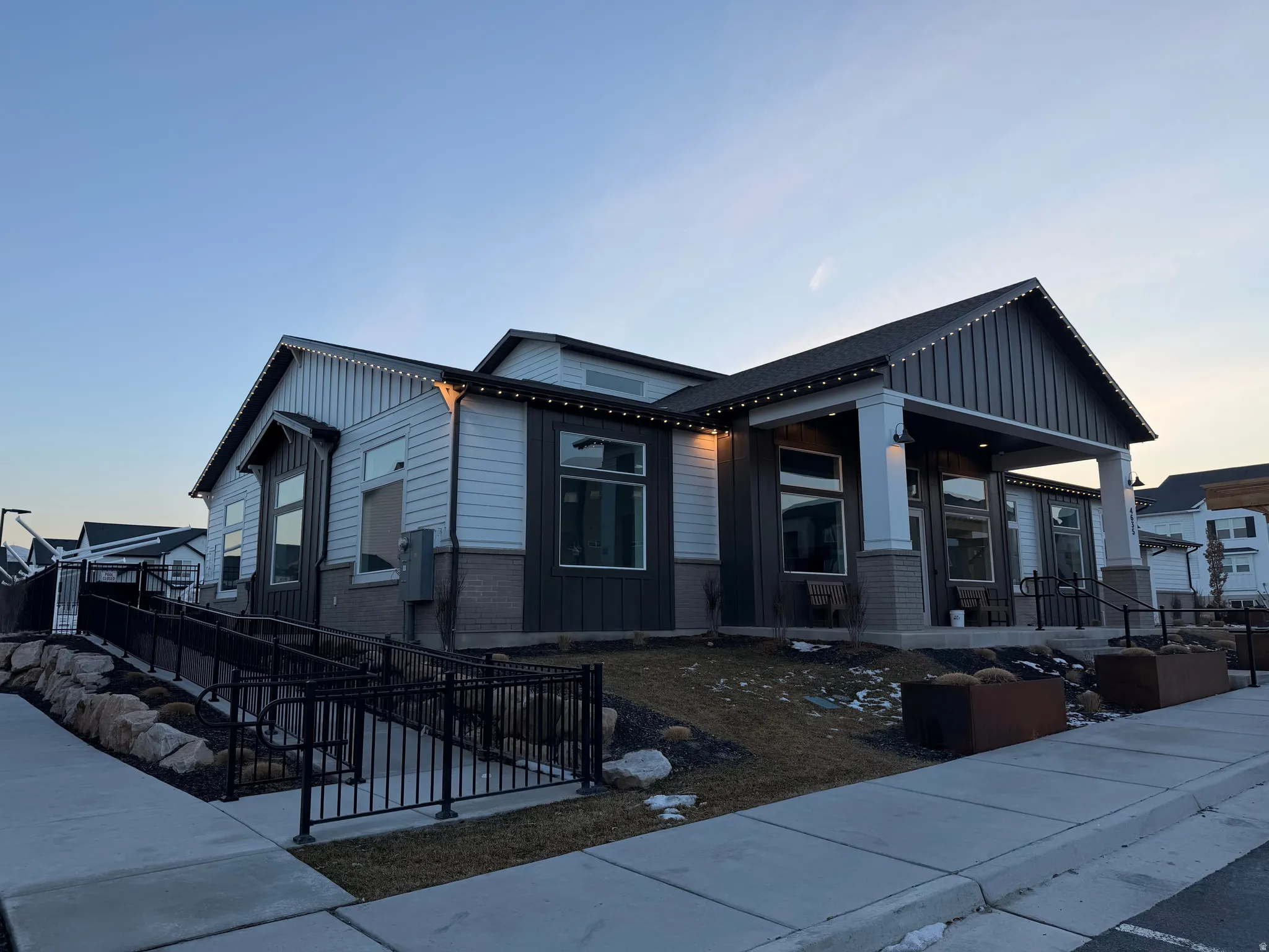 Contemporary exterior featuring multi-toned siding, a covered entry porch with columns, large picture windows, and a paved sidewalk