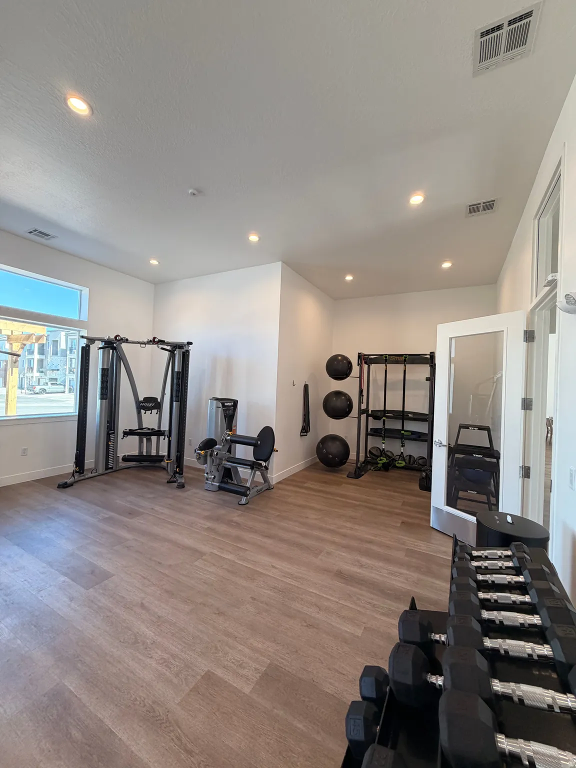 Spacious fitness area featuring wood-finish flooring, recessed lighting, and large windows