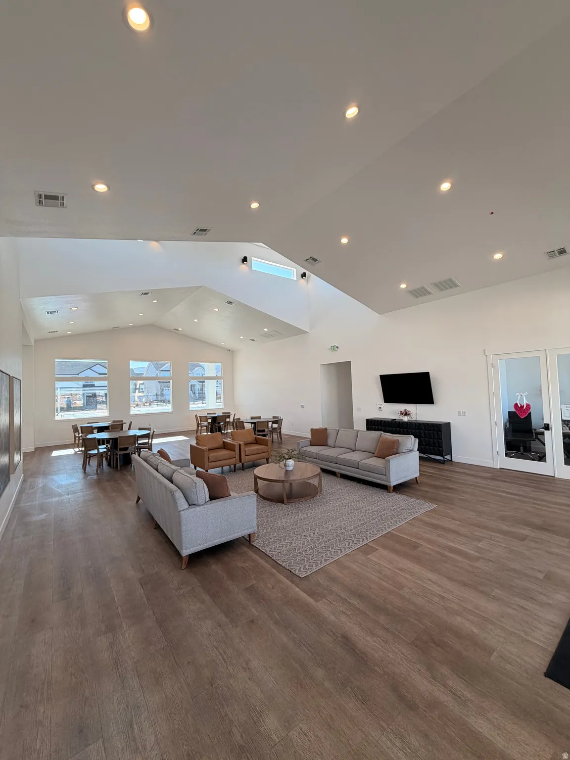Spacious common area featuring vaulted ceilings with recessed lighting and skylights, wood-finish flooring, and multiple window arrays