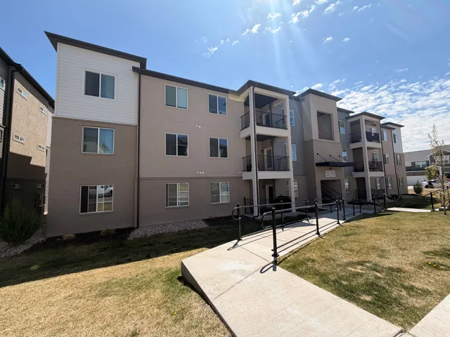 Multi-story building featuring a neutral-toned facade with white siding accents and black trim