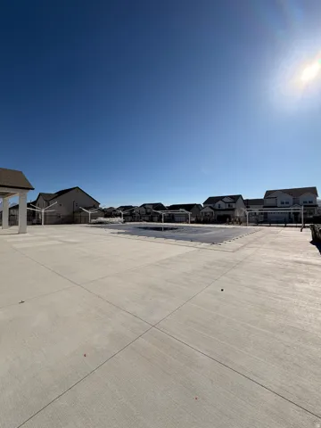 Expansive concrete patio surrounding a covered pool area