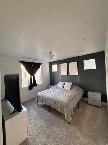 Carpeted room featuring a single window with dark drapery