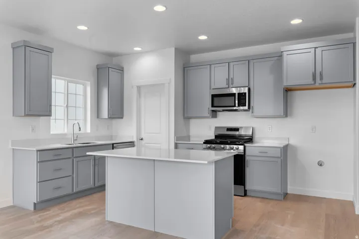 Modern kitchen featuring light gray cabinetry, white countertops, and wood-finish flooring