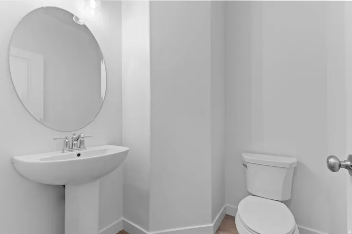 White pedestal sink with chrome faucet and oval mirror