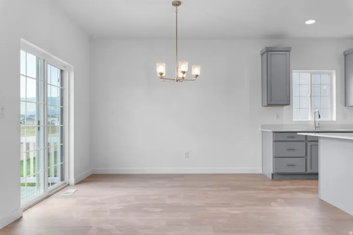 Open concept dining area featuring wood-finish flooring, a modern chandelier, and sliding glass doors to the exterior