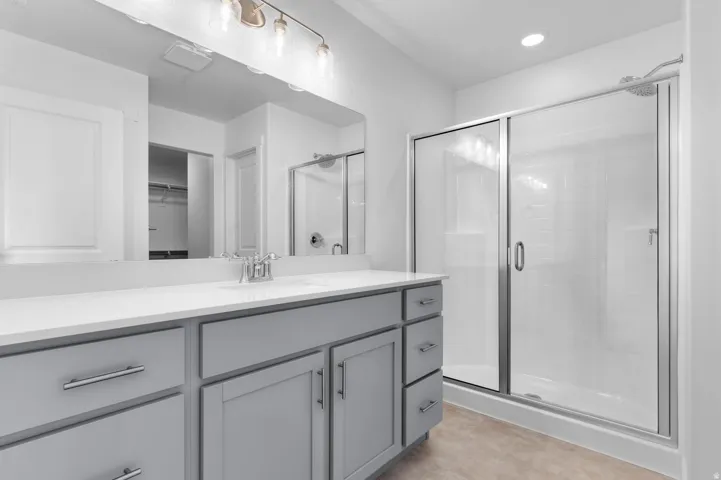 Bathroom featuring a spacious vanity with gray cabinetry, a white countertop, and a built-in sink