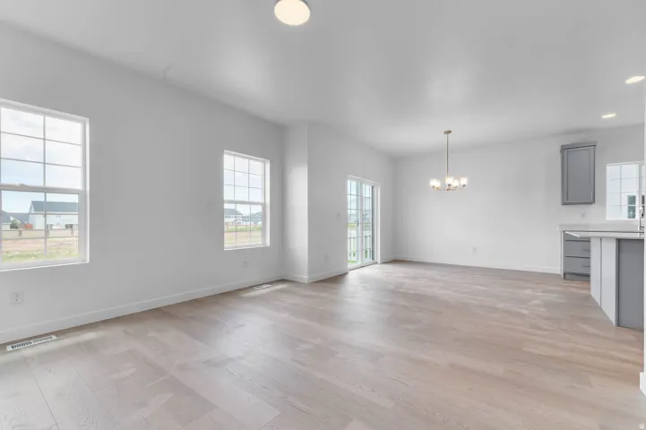 Open concept living space featuring light wood-finish flooring, multiple windows, and a sliding glass door