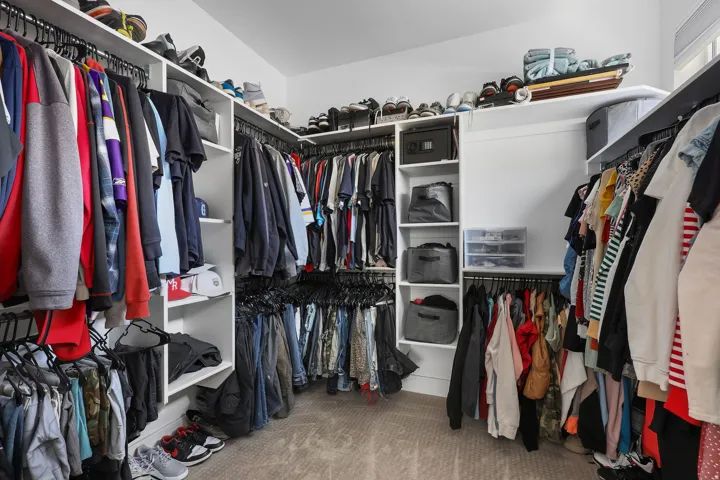 Custom closet system featuring multiple hanging rods, integrated shelving units, and carpet flooring
