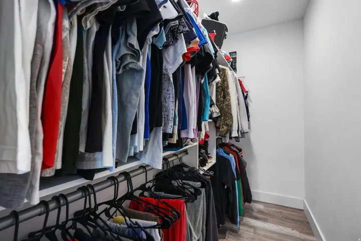 Walk-in closet featuring built-in shelving, multiple hanging rods, recessed lighting, and wood-finish flooring
