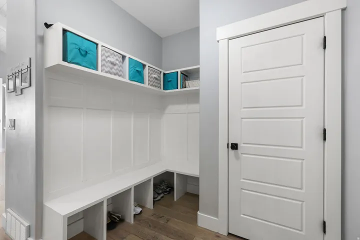 Built-in hall tree with integrated bench seating, cubby storage, upper shelving, and white paneling details