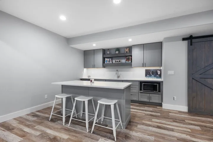 Entertainment space featuring a custom island with countertop seating, wood-finish flooring, and a built-in microwave
