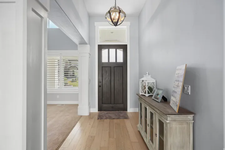 Entryway featuring a dark wood-finish door with glass inserts, wood-finish flooring, a contemporary orb chandelier, and crisp white trim details