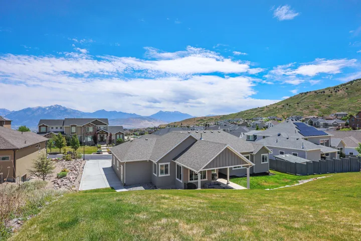 Contemporary ranch-style residence featuring a covered patio, a spacious concrete driveway, and a sloped grassy yard