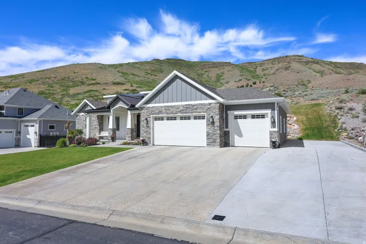 Contemporary residence featuring a stone and siding exterior, multiple garage bays, and a concrete driveway
