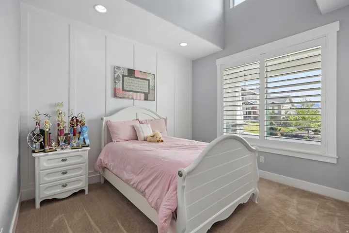Bedroom featuring board and batten wall detailing, recessed lighting, and a window with plantation shutters