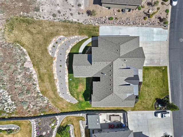 Expansive lot featuring a multi-gabled roofline, concrete driveway, and a decorative rock-lined pathway
