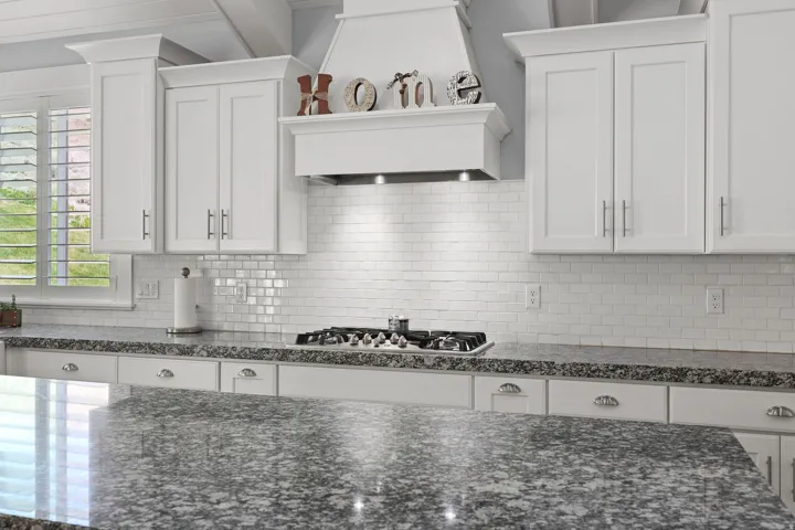 Kitchen featuring white shaker-style cabinetry, granite countertops, subway tile backsplash, and a built-in gas range with a matching range hood