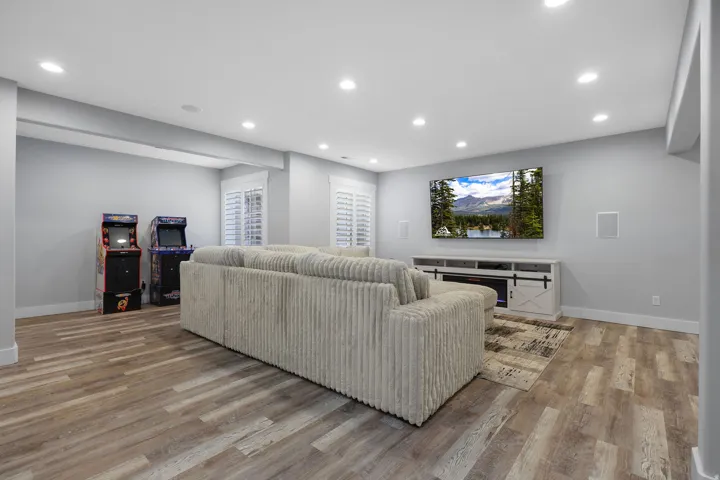 Spacious recreation area featuring wood-finish flooring, recessed lighting, and white baseboards