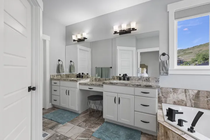 Double vanity with white cabinetry, stone countertops, and integrated sinks