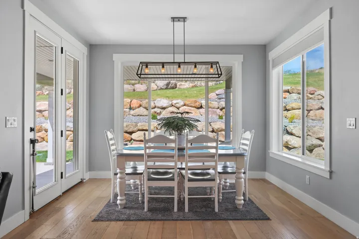 Dining area featuring wood-finish flooring, a modern linear chandelier, and light gray wall tones