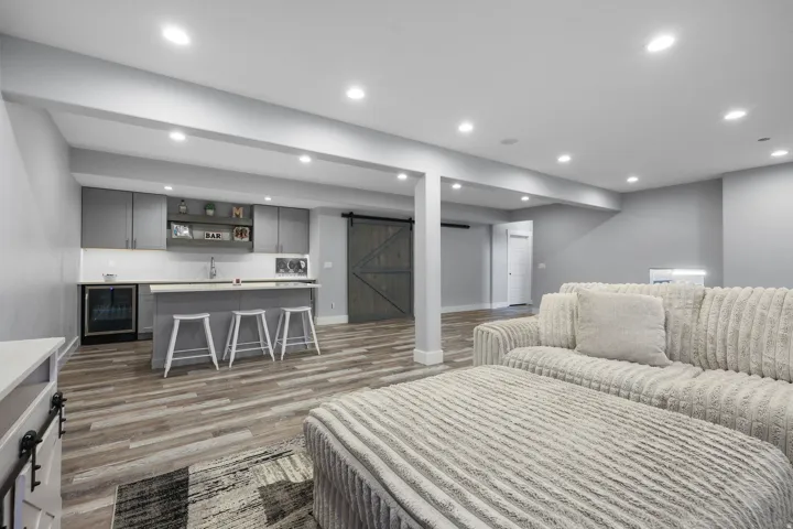 Recreation room featuring wood-finish flooring, a wet bar with gray cabinetry, a built-in beverage cooler, and recessed lighting