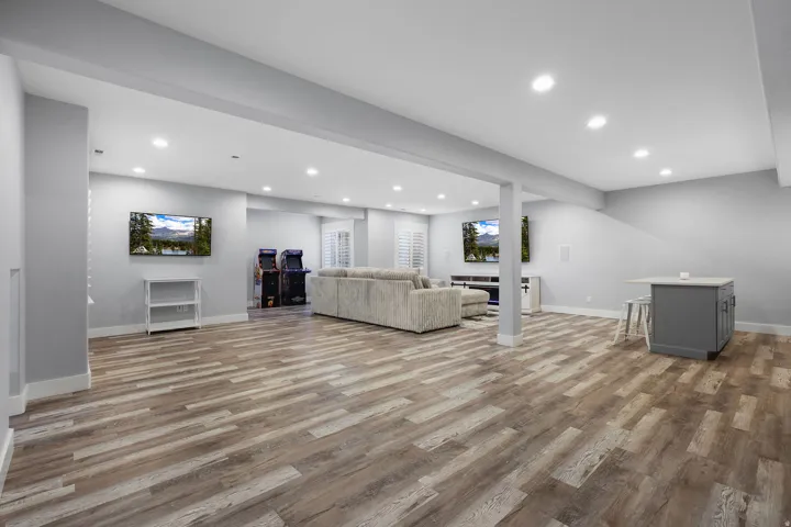 Expansive lower-level space featuring wood-finish flooring, recessed lighting, and a built-in island with countertop