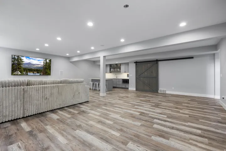 Spacious finished lower level featuring wood-finish flooring, recessed lighting, and a barn door entry