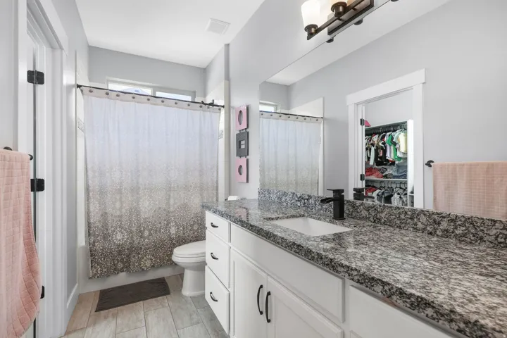 Bathroom featuring a light gray vanity with a dark speckled countertop, an undermount sink, and a matte black faucet