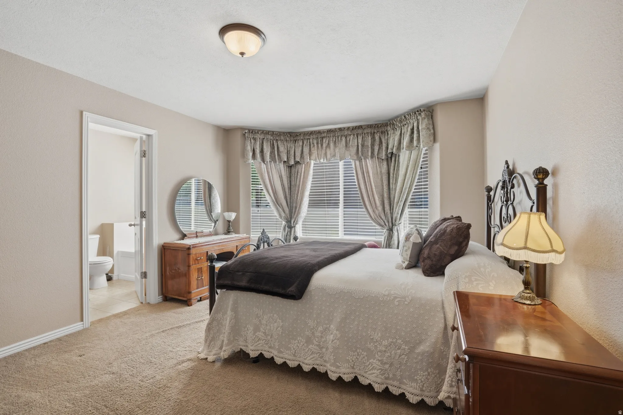 Plush carpeting throughout with a classic bay window featuring blinds and decorative valance