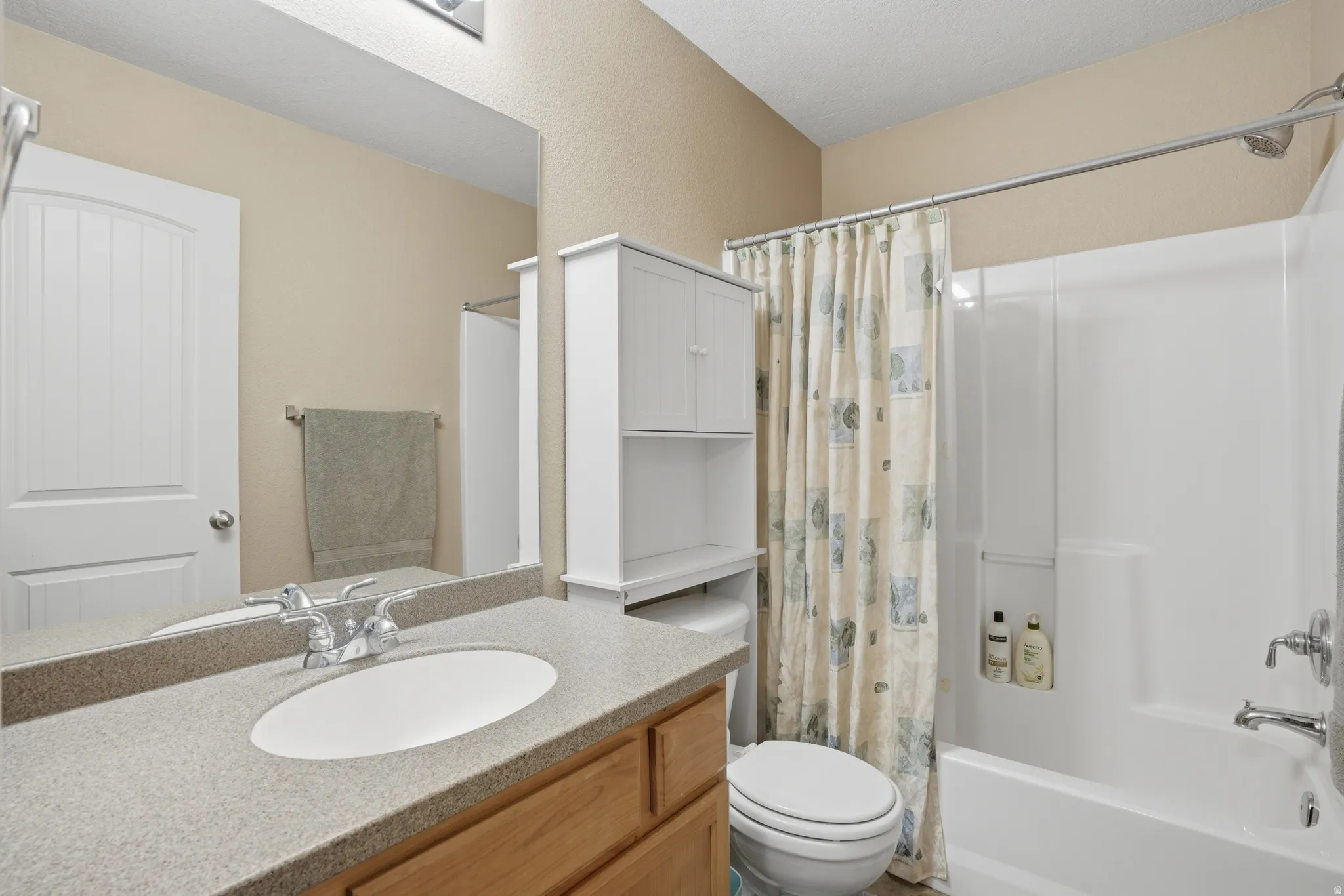 Bathroom with a wood-finish vanity, integrated oval sink, and a speckled countertop