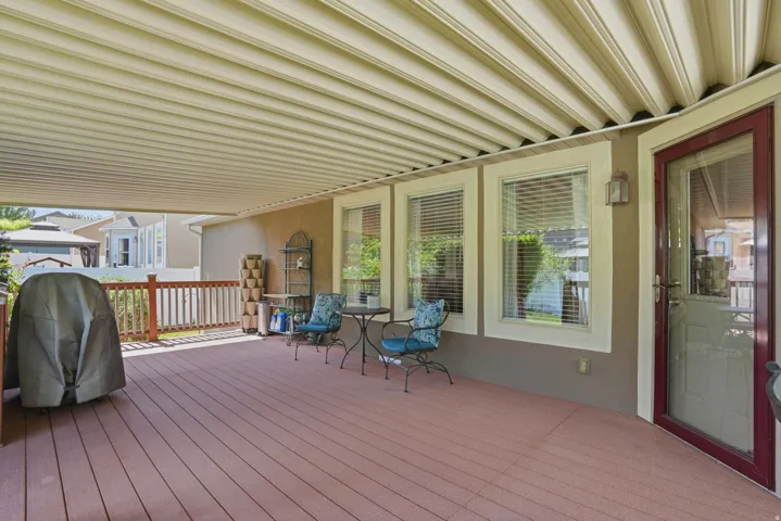 Expansive covered patio featuring wood-finish decking, a full privacy railing, and direct access to interior spaces
