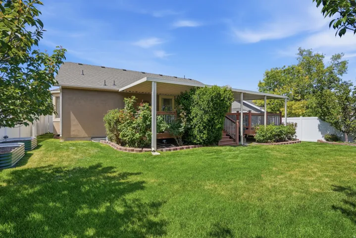 Expansive backyard featuring a covered deck, wood-finish decking, and mature landscaping