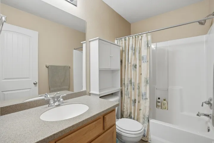 Bathroom with a wood-finish vanity, integrated oval sink, and a speckled countertop