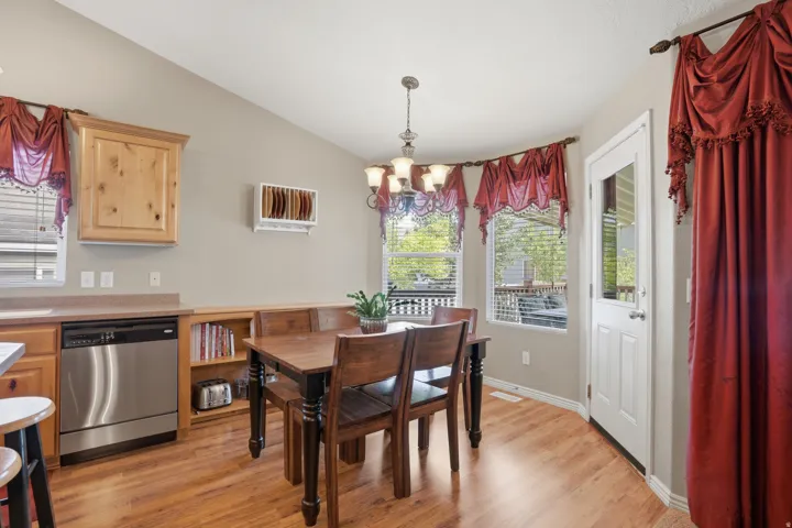 Dining area featuring wood-finish flooring, a contemporary chandelier, and a built-in bench seating with open shelving