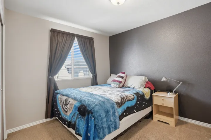 Neutral-toned walls with a contrasting accent wall, carpeted flooring, and a window with blinds