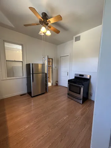 Kitchen area featuring wood-finish flooring, a stainless steel refrigerator, and a stainless steel range