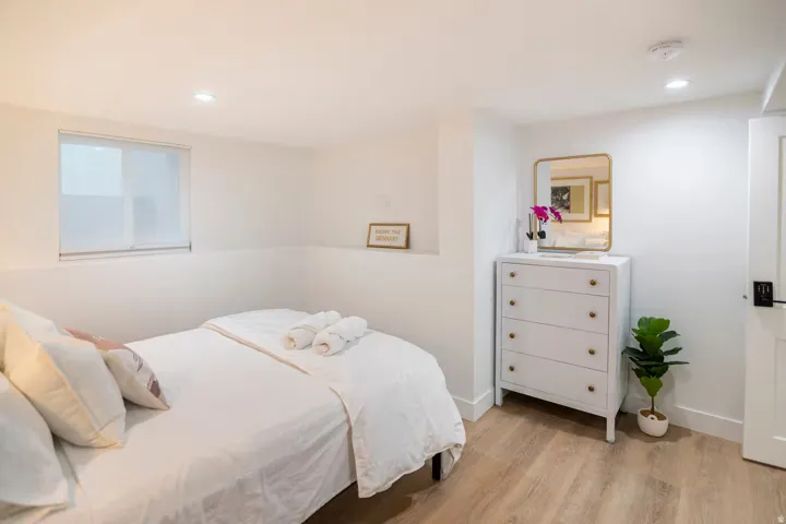 Bedroom featuring wood-finish flooring, recessed lighting, and a window with a roller shade