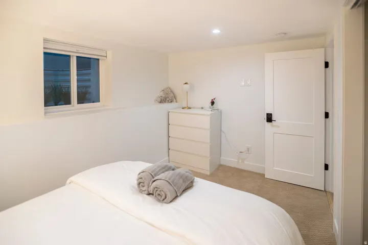 Inviting room featuring a single window, white paneled door with dark hardware, recessed ceiling lighting, and carpet flooring