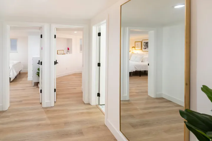 Hallway featuring light wood-finish flooring, white walls, multiple doorways, and recessed lighting