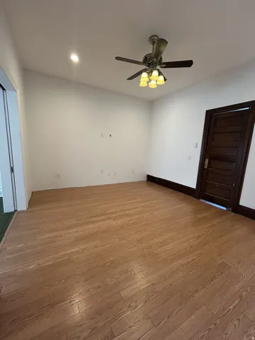 Spacious room featuring wood-finish flooring, a multi-light ceiling fan, and recessed lighting